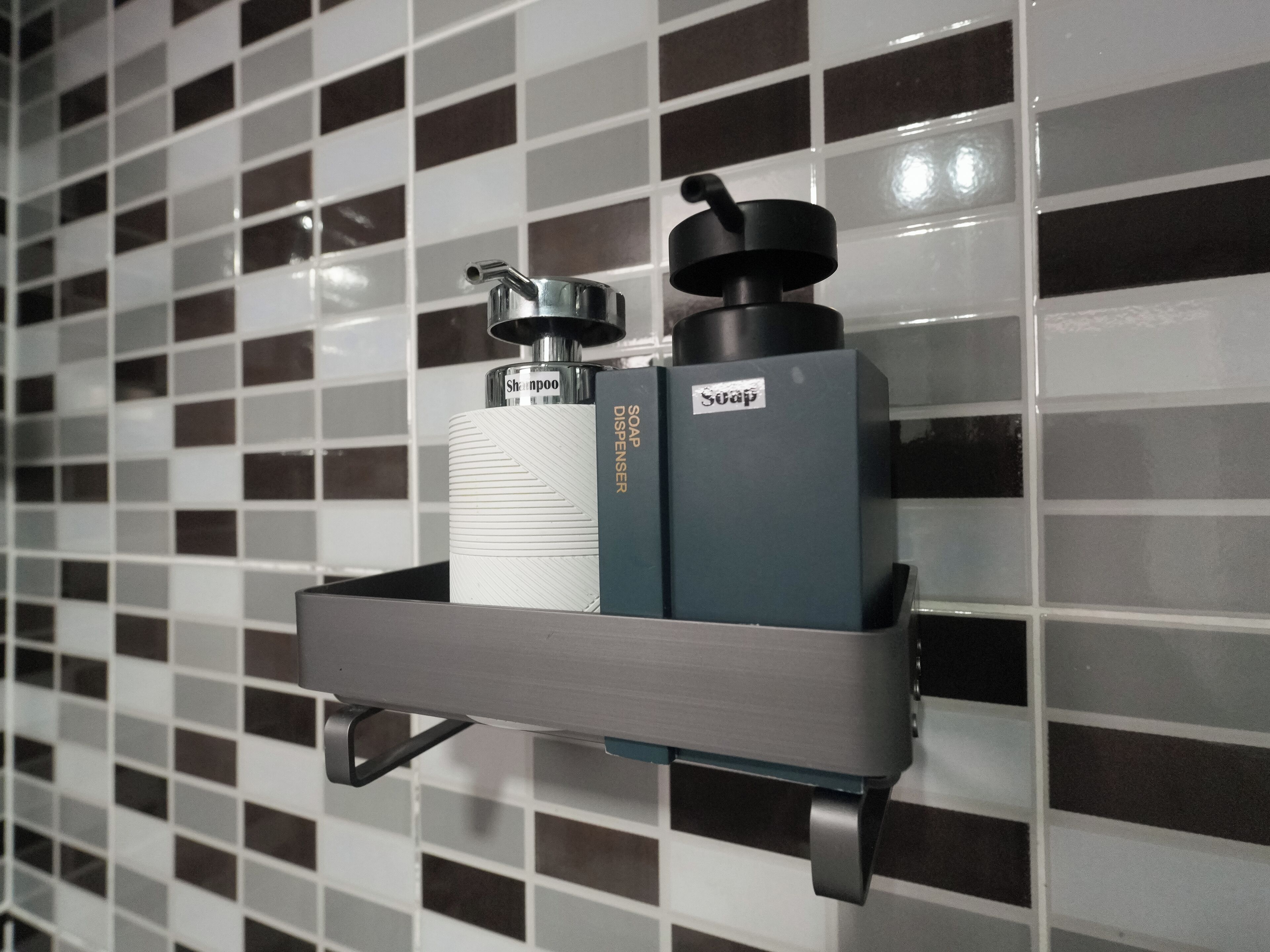 A bathroom shelf with a shampoo bottle, a soap dispenser, and a water bottle.