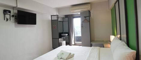 Una habitación de hotel con cama, televisión, armario, lavabo y ventana.
