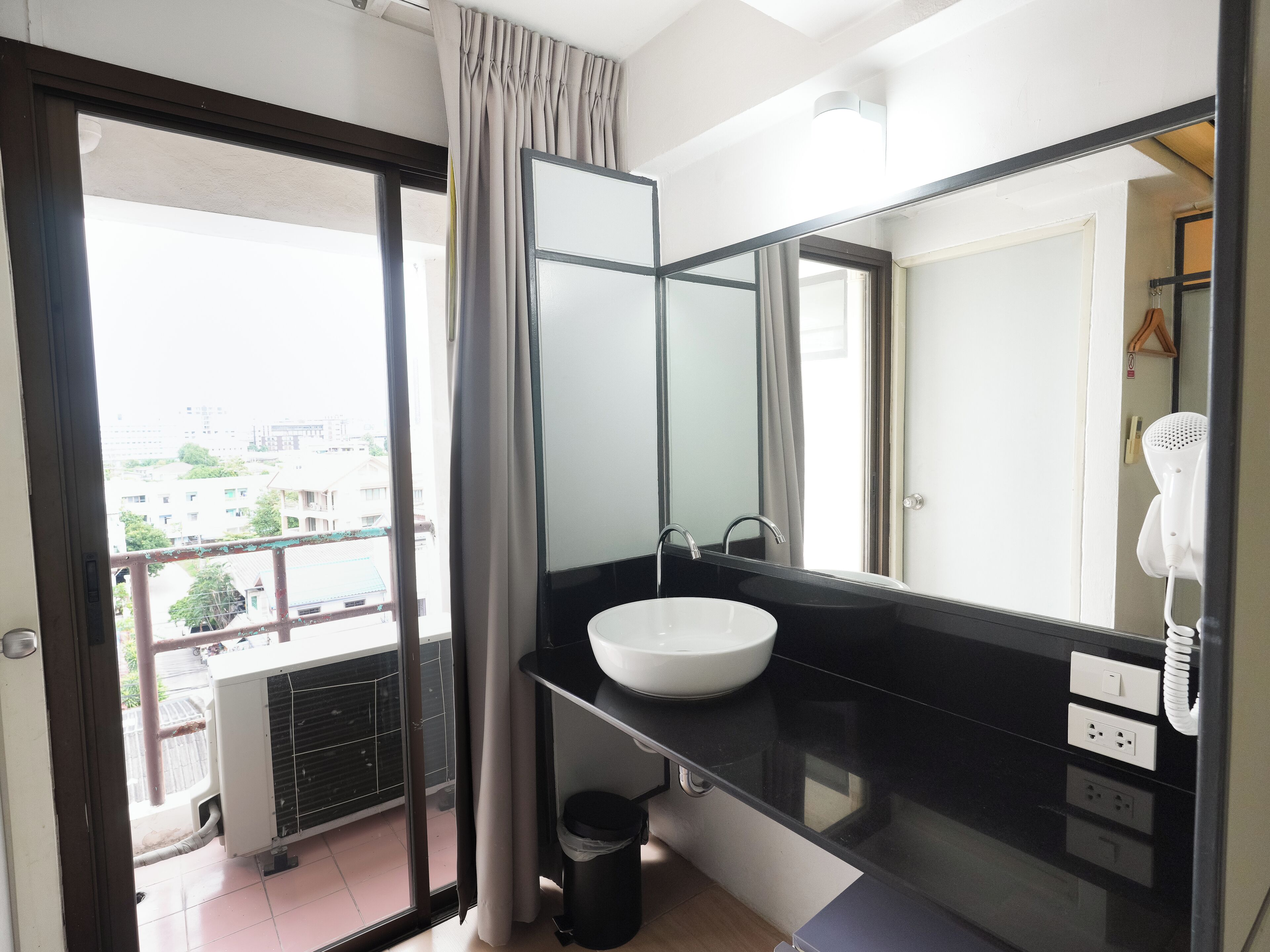 Une salle de bain moderne avec un grand miroir, un lavabo blanc et un sèche-cheveux.