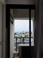 A view from a balcony with a metal railing, overlooking a residential area with various buildings and a clear sky.