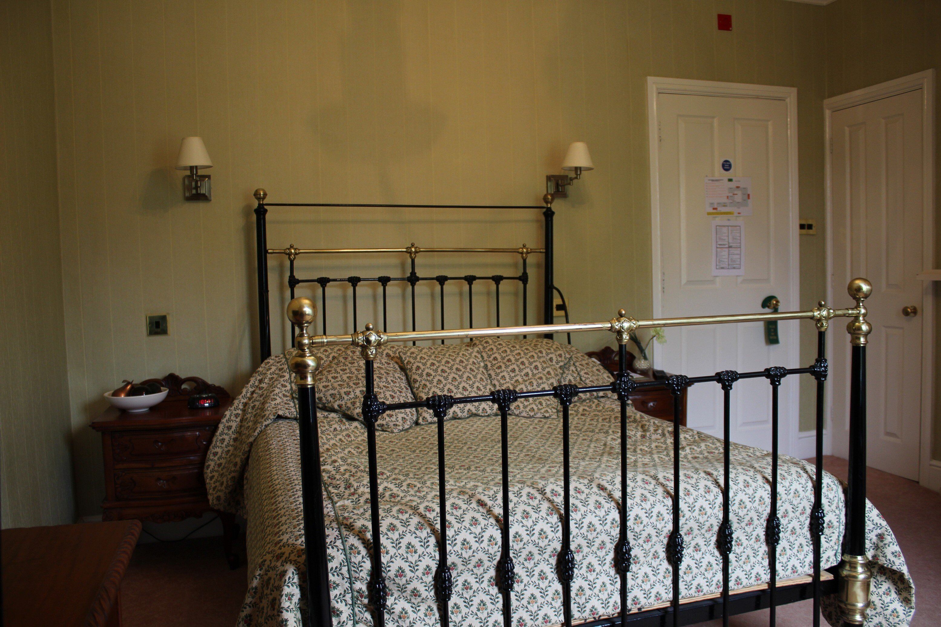 A bedroom with a four-poster bed, a nightstand, and a dresser.