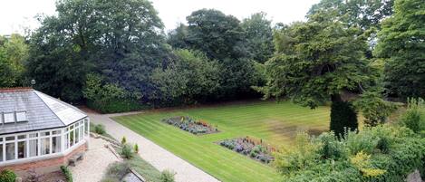 A well-maintained garden with a lawn, flower beds, and a conservatory.