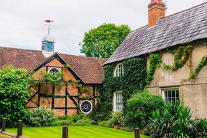 A traditional Tudor-style building with a thatched roof, a visible chimney, and a weather vane. - The Old Rectory (Shrewsbury)