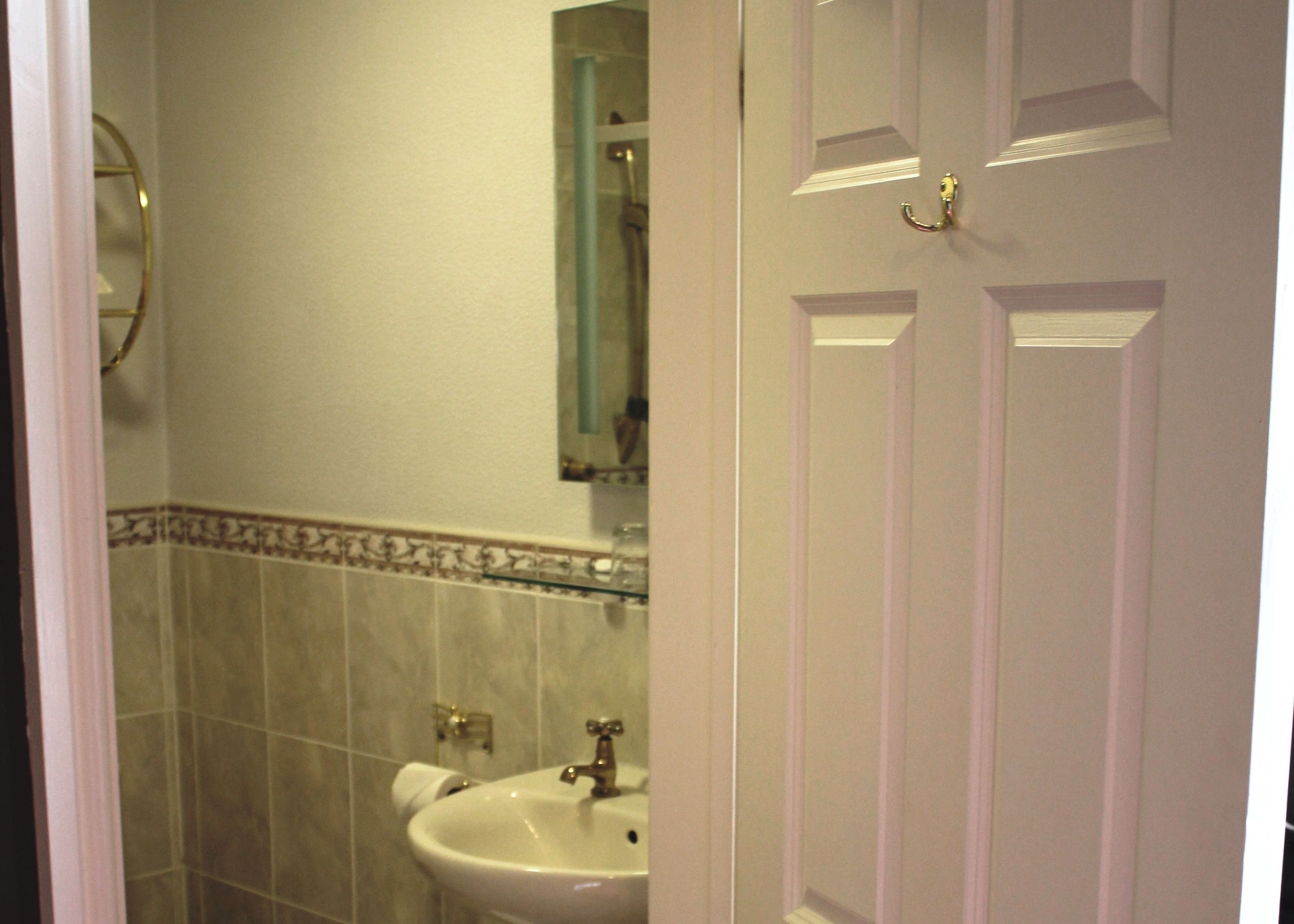 A bathroom with a sink, mirror, and tiled walls.