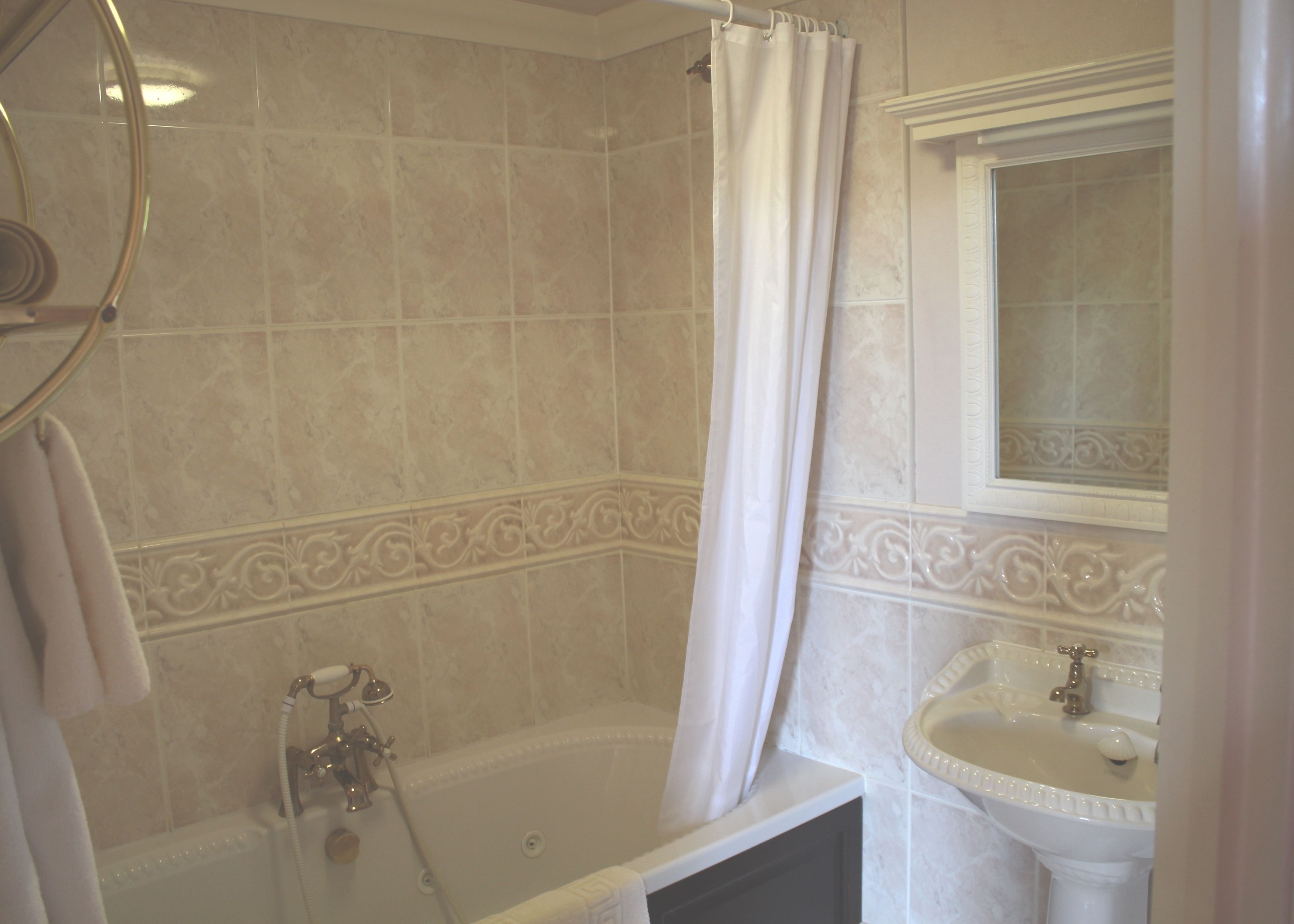 A bathroom with a bathtub, a shower curtain, a sink, and a mirror.