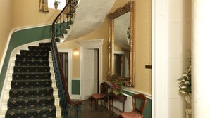 A grand staircase with ornate railings, a large mirror, and a floral arrangement.