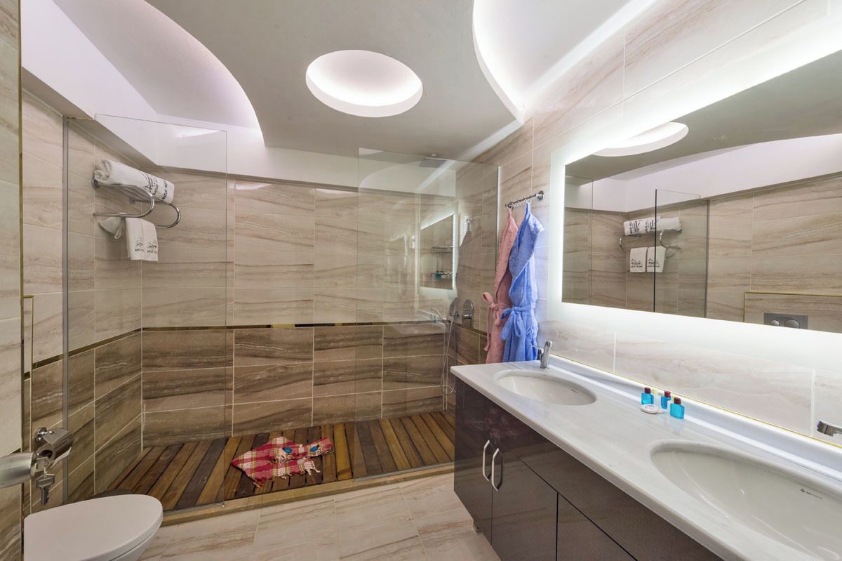 Un baño moderno con ducha envuelta en vidrio, suelo de madera y un espejo grande.