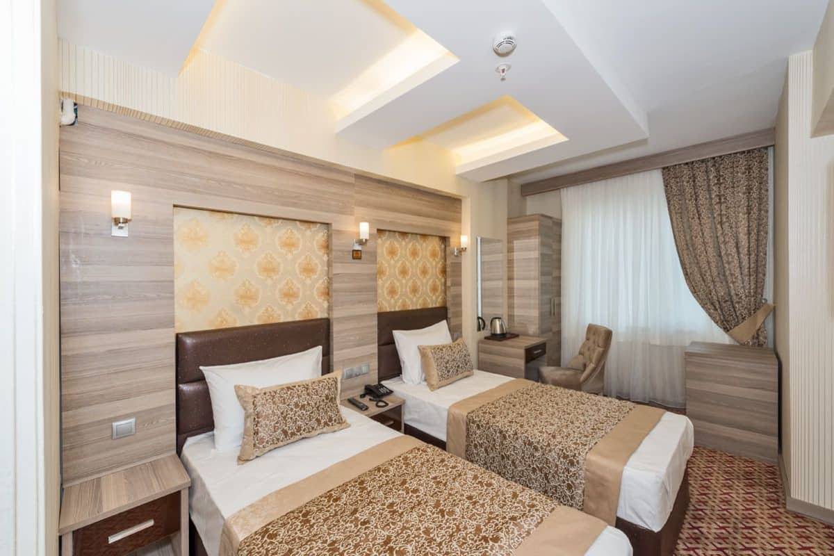 A hotel room with two beds, a chair, a nightstand, and a mirror.
