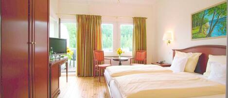 Ein Hotelzimmer mit einem großen Bett, einem Schreibtisch mit Fernseher, einer Kristallleuchtre und einem Gemälde an der Wand.