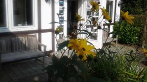 A building with large windows, a bench outside, and yellow flowers in the foreground. - Landhaus Bode (Lübeck)