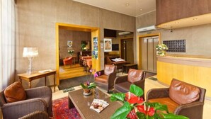 Un vestíbulo de hotel con mostrador de recepción, área de descanso y comedor.