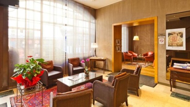 Un amplio vestíbulo de hotel con un gran ventanal, asientos cómodos y una recepción.