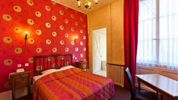 A room with a bed, a desk, and a chair. There is a window with curtains, a radiator, and a door.