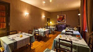 Comedor con varias mesas dispuestas para comidas, sillas de madera y un ambiente cálido con luces empotradas en el techo.