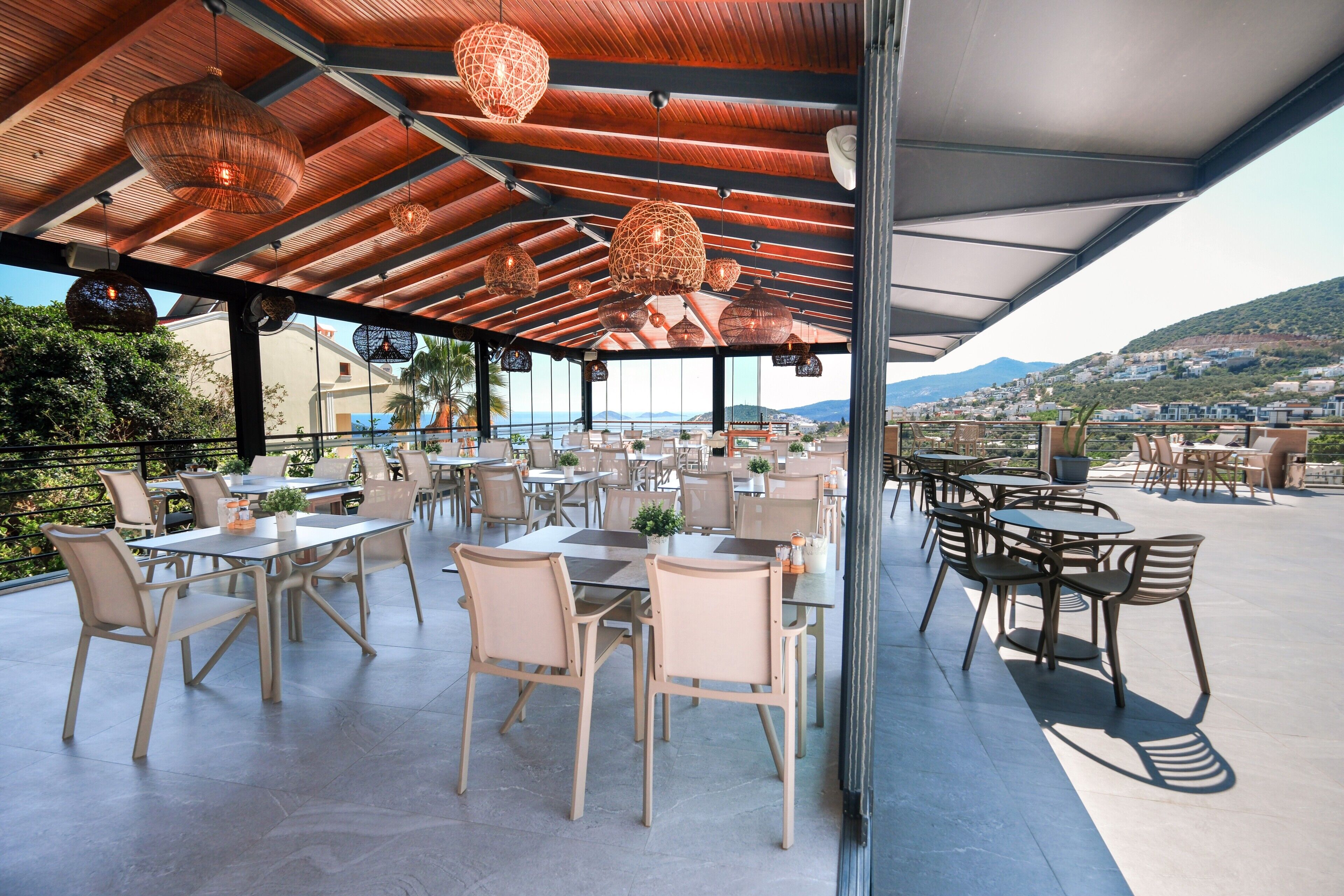 Un espace de restauration en plein air avec des tables et des chaises, un coin salon abrité et une vue sur le paysage.