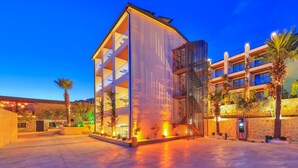 A modern building with multiple floors, large windows, and a parking area with a charging station. - Samira Resort Hotel Aparts & Villas (Kas)