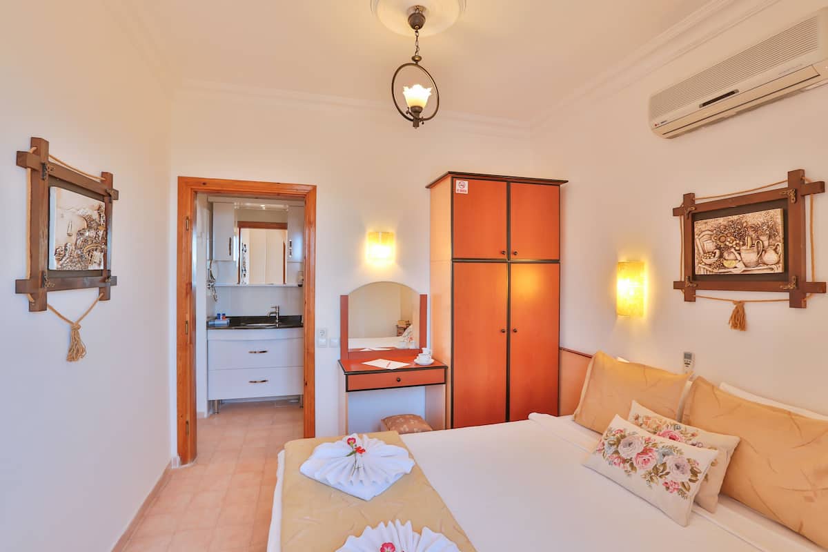 Ein Hotelzimmer mit Bett, Schreibtisch, Kleiderschrank und einem durchgegangenen Tür sichtbaren Badezimmer.