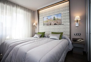 Ett hotellrum med två sängar, en tavla på väggen och ett nattduksbord med en lampa.