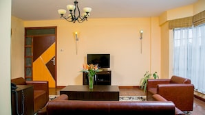 A living room with a sofa set, a coffee table, a TV, and a chandelier.