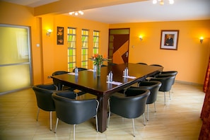 A conference room with a long table, black chairs, and a vase with flowers.