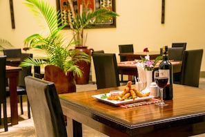 A dining table with a plate of food, a bottle of wine, and a vase with flowers.