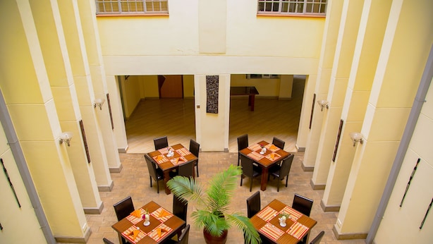 A dining area with multiple tables and chairs, a central potted plant, and a tiled floor.