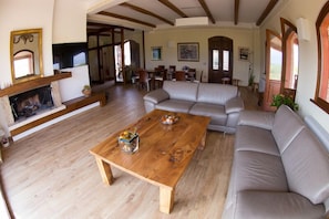 A spacious living room with a wooden coffee table, a beige sofa, and a fireplace. - Tenuta Terre dei Latini (Segni)