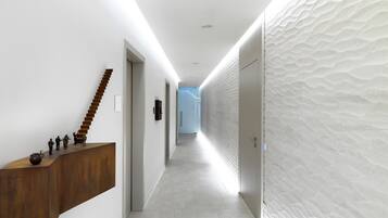 A modern hallway with a wooden reception desk, a staircase, and a textured wall.