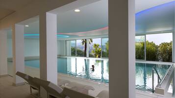Relax by the pool surrounded by expansive views of palm trees and distant hills.