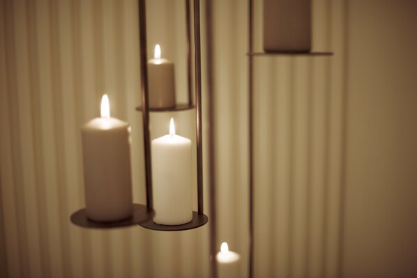 Tres velas encendidas sobre un soporte fijado a la pared.