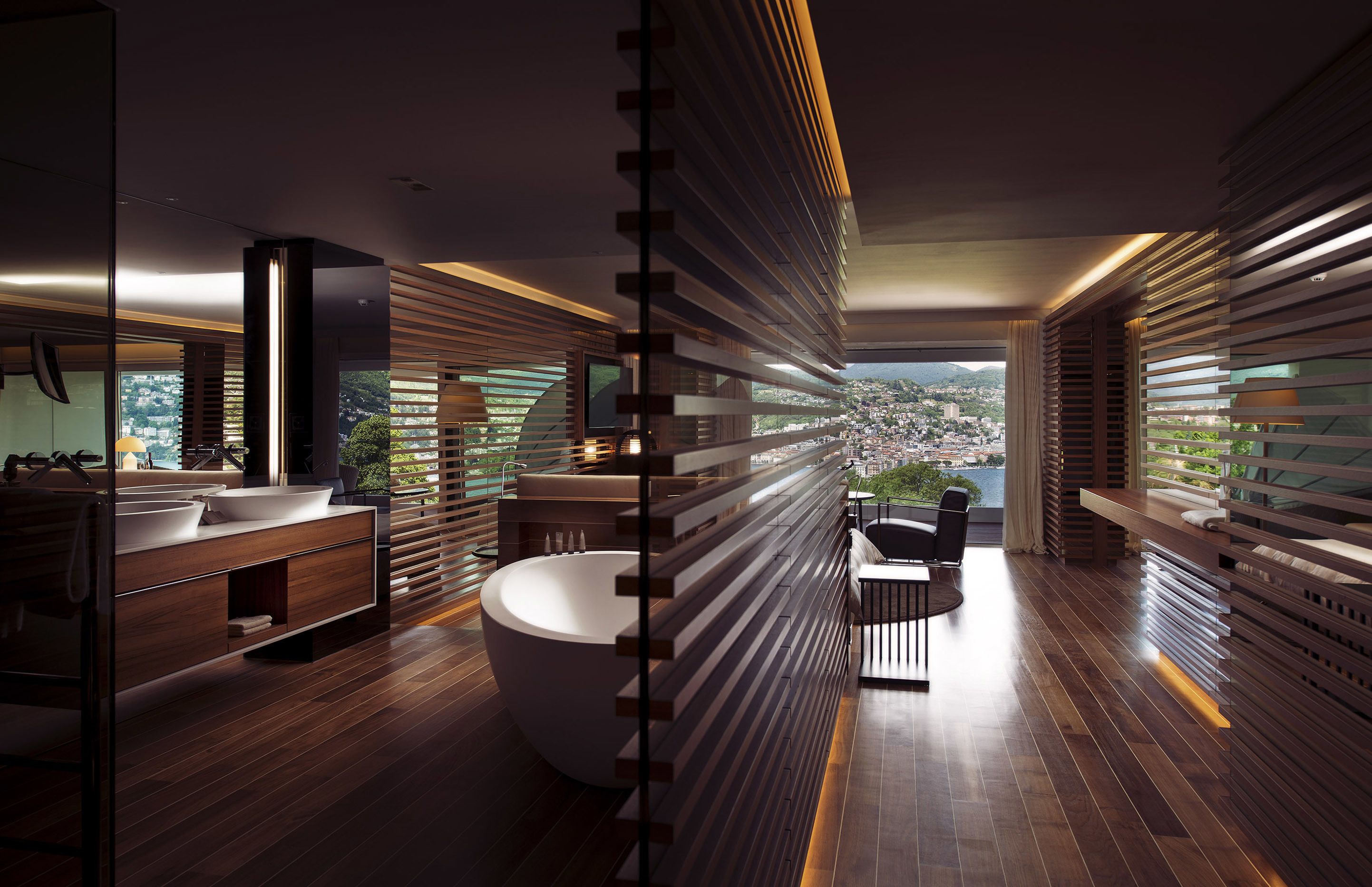 A modern bathroom with a large bathtub, wooden slats, and a view of the city.