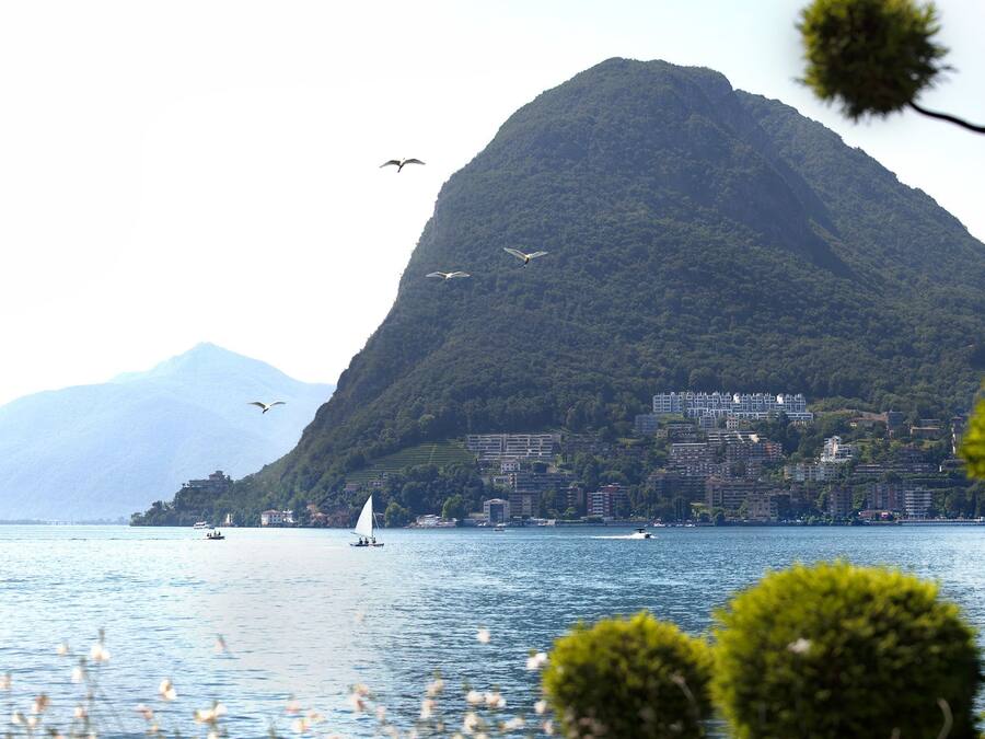 A coastal view with a mountain, boats, and a cityscape in the background.
