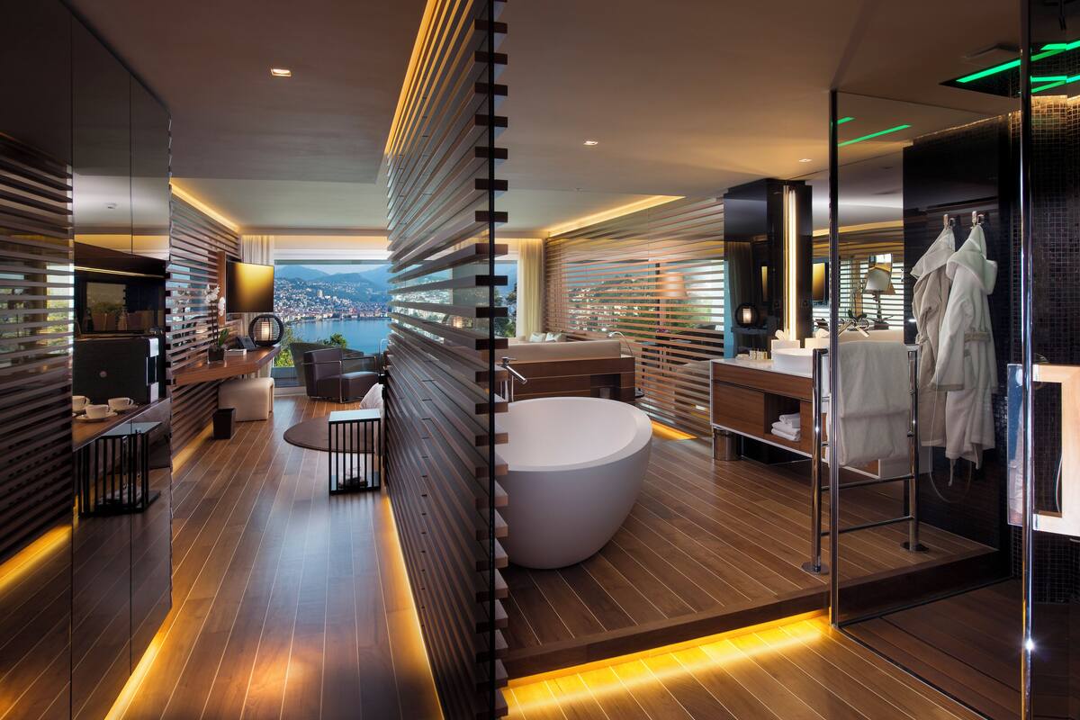 A modern bathroom with a large bathtub, a glass-enclosed shower, and a view of a cityscape.