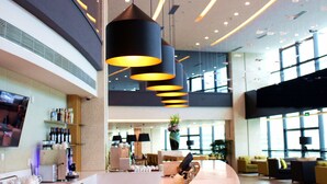 Eine moderne Hotelhalle mit einer gebogenen Rezeption, mehreren Sitzbereichen und Pendelleuchten.