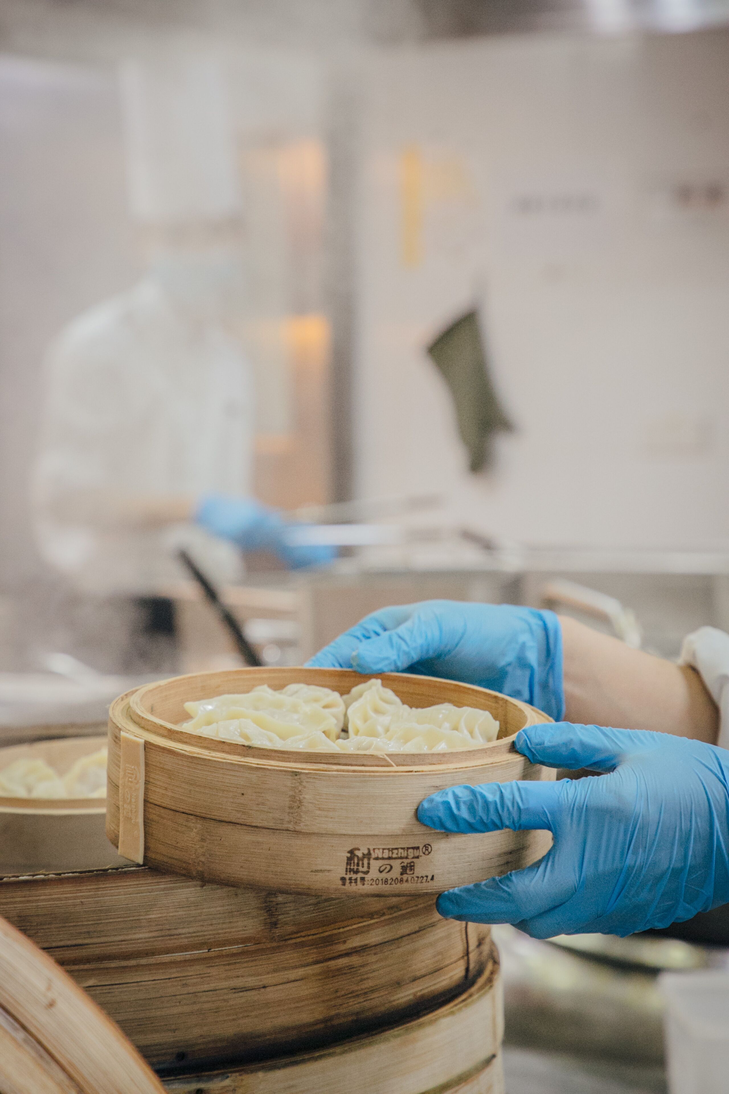 A person wearing blue gloves handling a wooden container with a label.