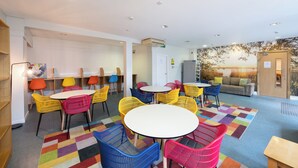 Un'area lounge moderna con sedie e tavoli colorati, un divano e un murale sulla parete.