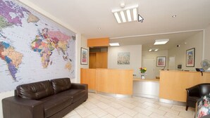 Un'area reception con una mappa del mondo, un divano in pelle marrone, una scrivania reception in legno e una sedia nera.