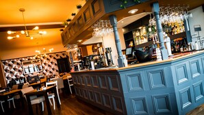 A bar area with a blue counter, multiple seating arrangements, and a geometric patterned wall. - The Brunswick (Shanklin)