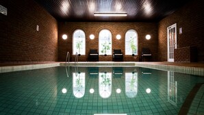 An indoor swimming pool with a tiled floor, brick walls, and arched windows. - The Brunswick (Shanklin)