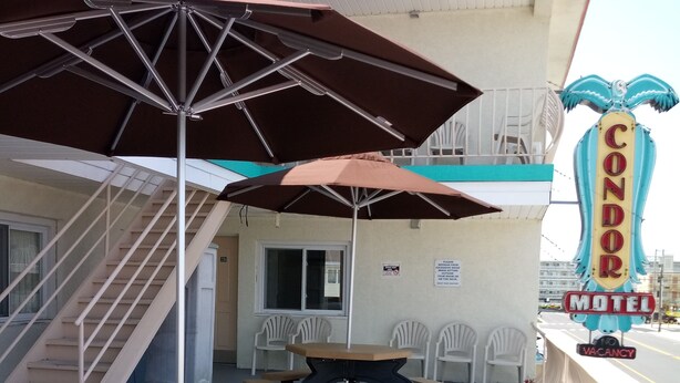 Een buitenzitgedeelte met picknicktafels en parasols bij een motel.