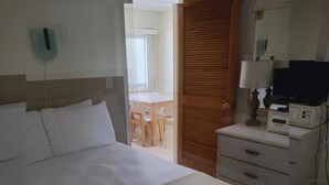 Een hotelkamer met een bed, bureau, televisie en minibar.