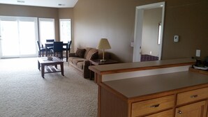 A spacious living room with a sofa, a coffee table, and a dining area with chairs and a table. - Dunmaglas Golf Course (Charlevoix)