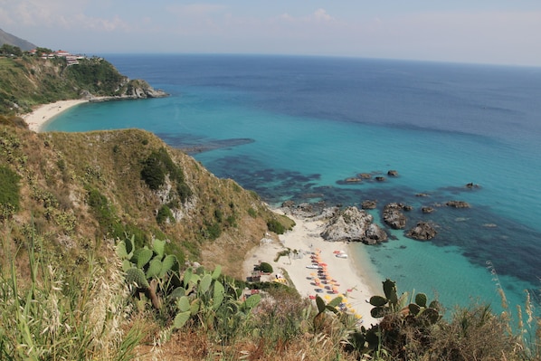 Eine Küstenlandschaft mit Strand, Felsen und Vegetation.