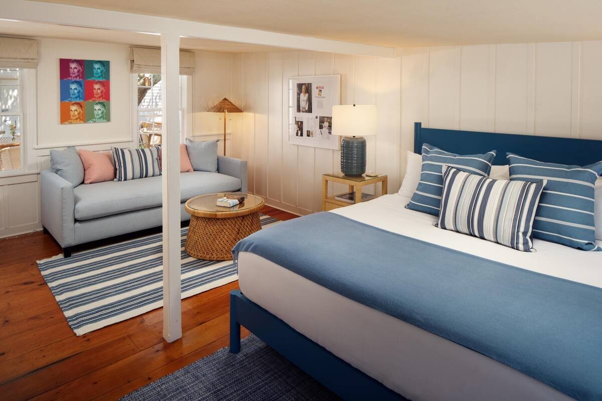 Quarto moderno com cama, sofá, mesa de centro redonda e luminária.