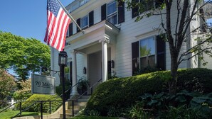 A two-story building with a sign reading "76 Main Ink Press Hotel" and an American flag.