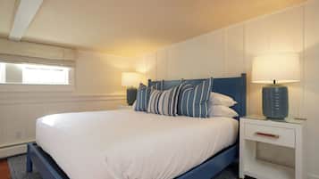 Un lit bien fait, avec une tête de lit bleue, du linge de lit blanc et deux lampes de chevet.