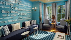 A living room with a teal accent wall, two sofas, a coffee table, and a vintage typewriter. -  76 Main Ink Press Hotel (Nantucket)