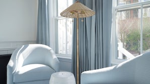 A room with two light blue armchairs, a floor lamp with a woven shade, and a window with light blue curtains. -  76 Main Ink Press Hotel (Nantucket)