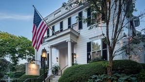 A two-story hotel with a white facade, a flagpole with an American flag, and a sign reading "76 Main Ink Press Hotel". -  76 Main Ink Press Hotel (Nantucket)