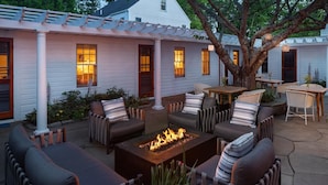 An outdoor patio area with a fire pit, seating, and a pergola. -  76 Main Ink Press Hotel (Nantucket)